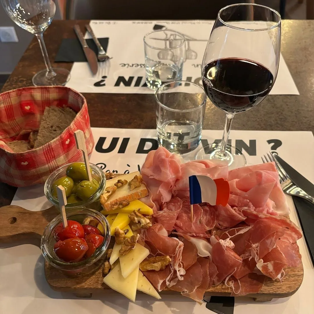 Une planchette de charcuterie et fromages avec un verre de rouge